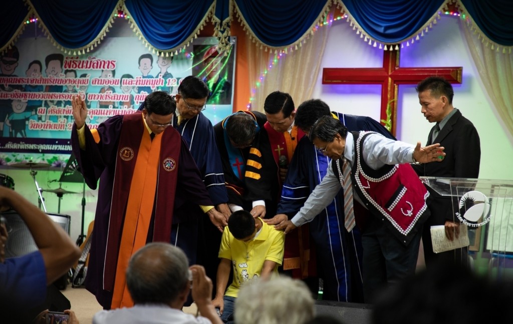 1阿杜一年前脫困後，參加教會主日，牧師帶領感謝讚美，並為他按手禱告。（照片來源：Compassion Thailand ／ Piyamary Shinoda）