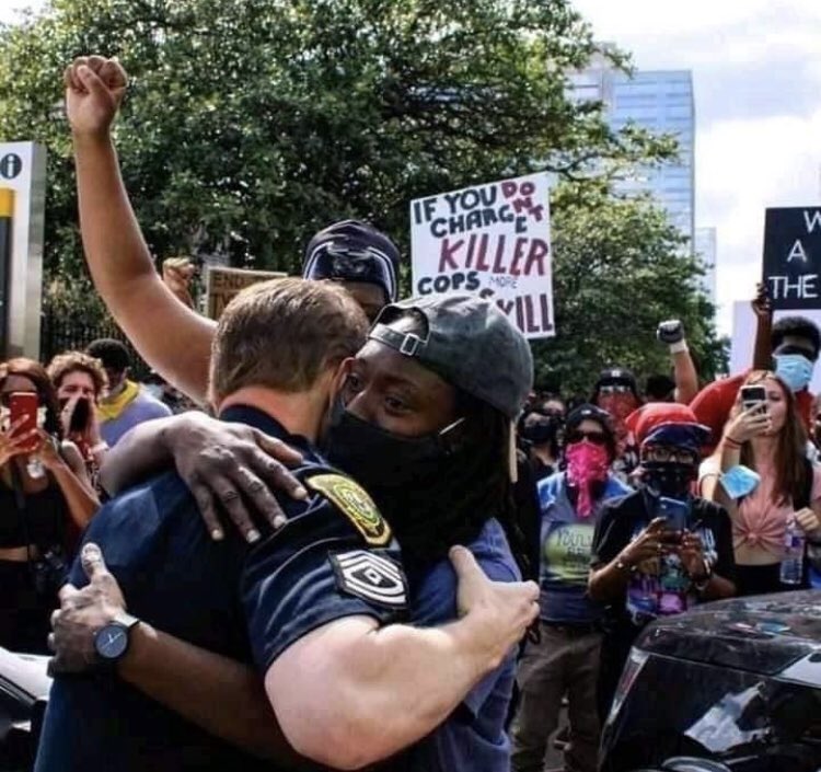 參加和平示威的非裔男子擁抱白人警察。（圖／twitter@Tendencia Noticias）