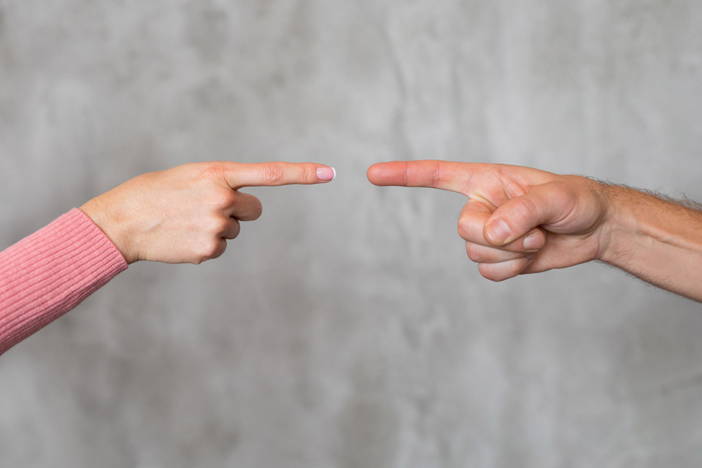 Man and woman's fingers pointing at each other