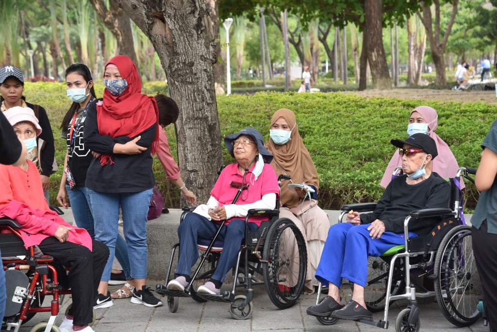 外籍移工用輪椅推著長輩，帶他們到公園曬太陽。(謝宜汝攝影)