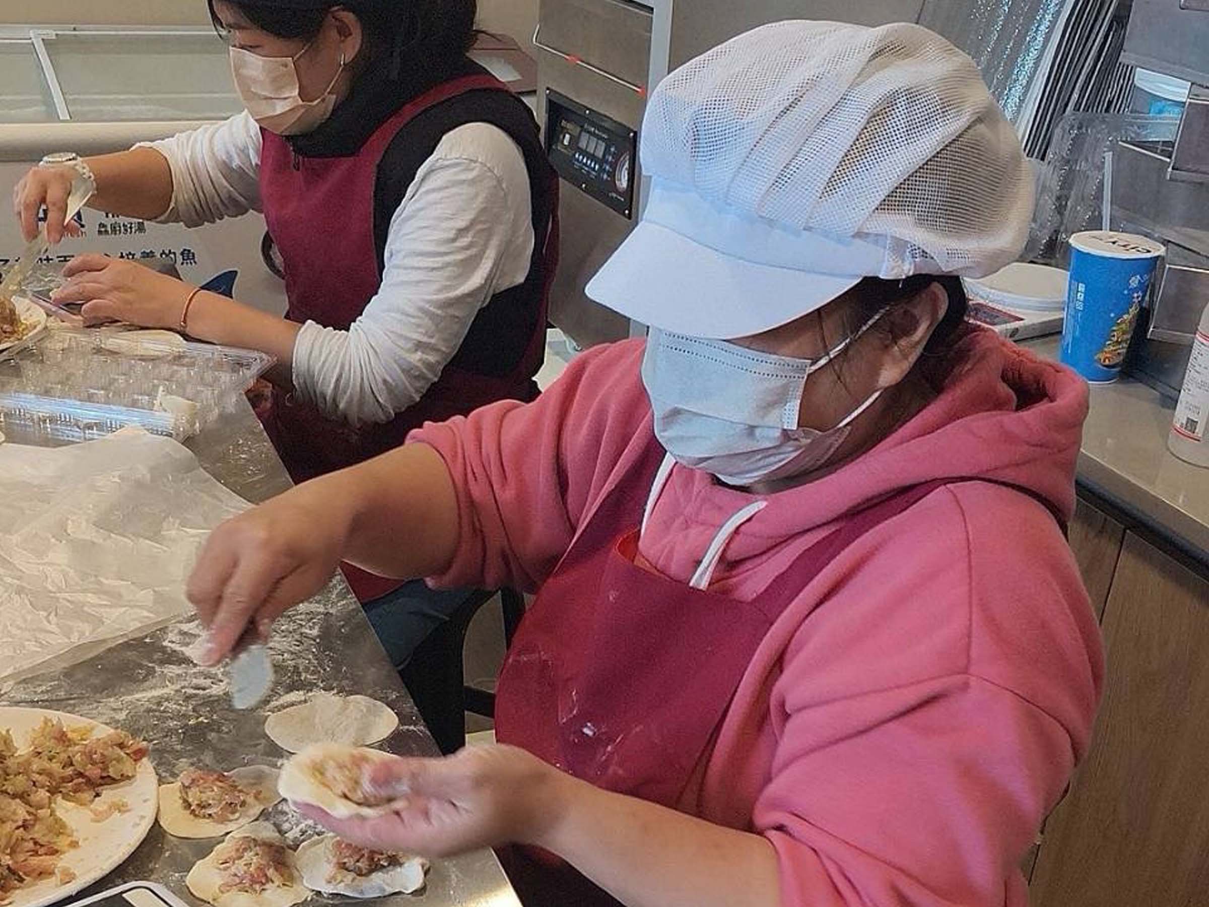 單親媽媽阿華（圖右）在萬里孫理蓮紀念營地廚房學習製作水餃，透過以工「帶振」計畫，兼顧家庭並穩定收入。（芥菜種會提供）