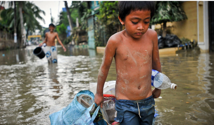 一名男孩在馬尼拉颱風過後拖著財物穿過被洪水淹沒的街道。（圖片來源﹕ADB）