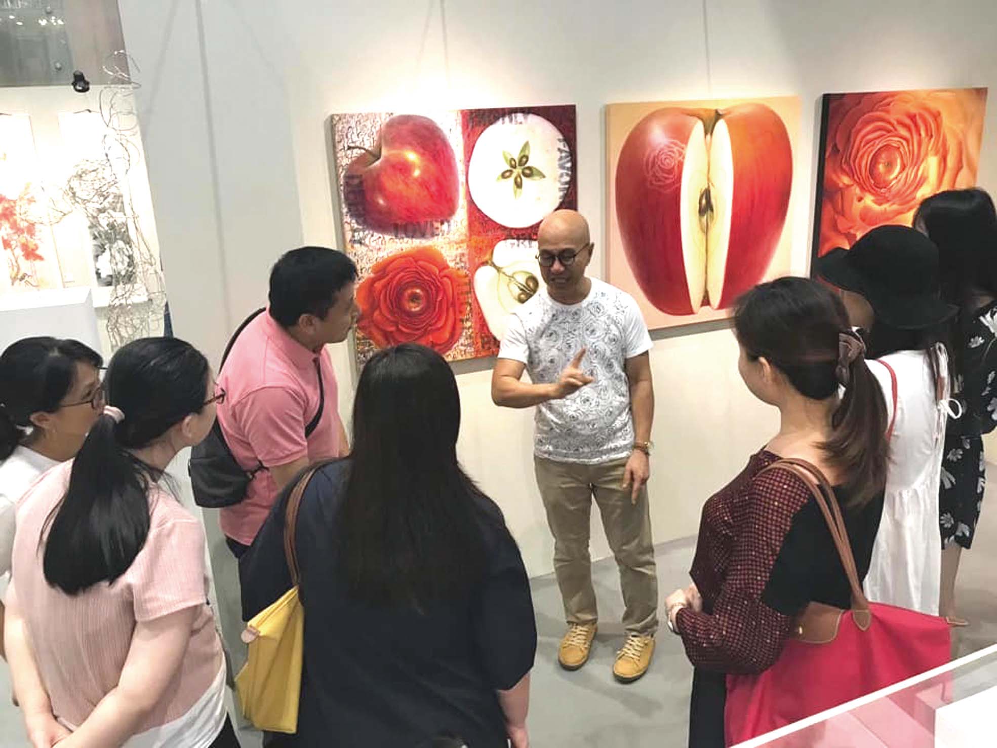 畫家在新加坡「祝福亞洲」藝術展上向會眾分享作品內容。
