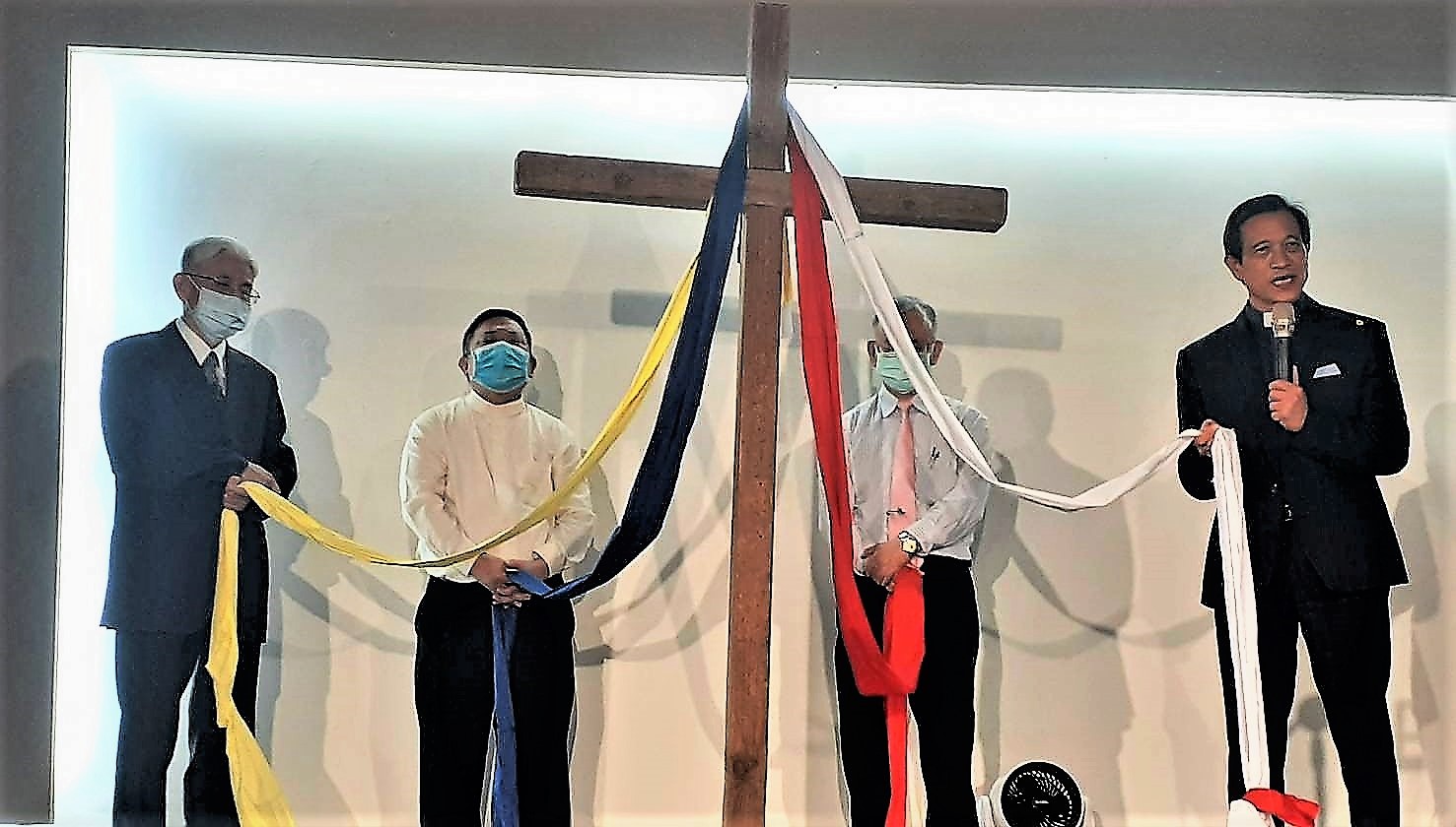 代表原住民、客家、閩南、外省的四位牧者手持十字架前的布條，象徵在十字架愛裡的合一。(圖/余慶榮牧師提供)