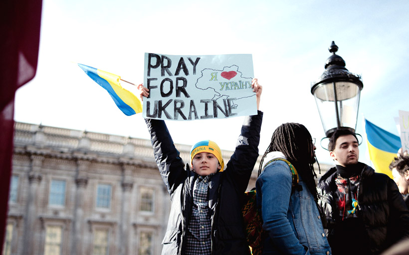 民眾高舉「為烏克蘭禱告」海報。（Photo by Chuko Cribb on Unsplash）
