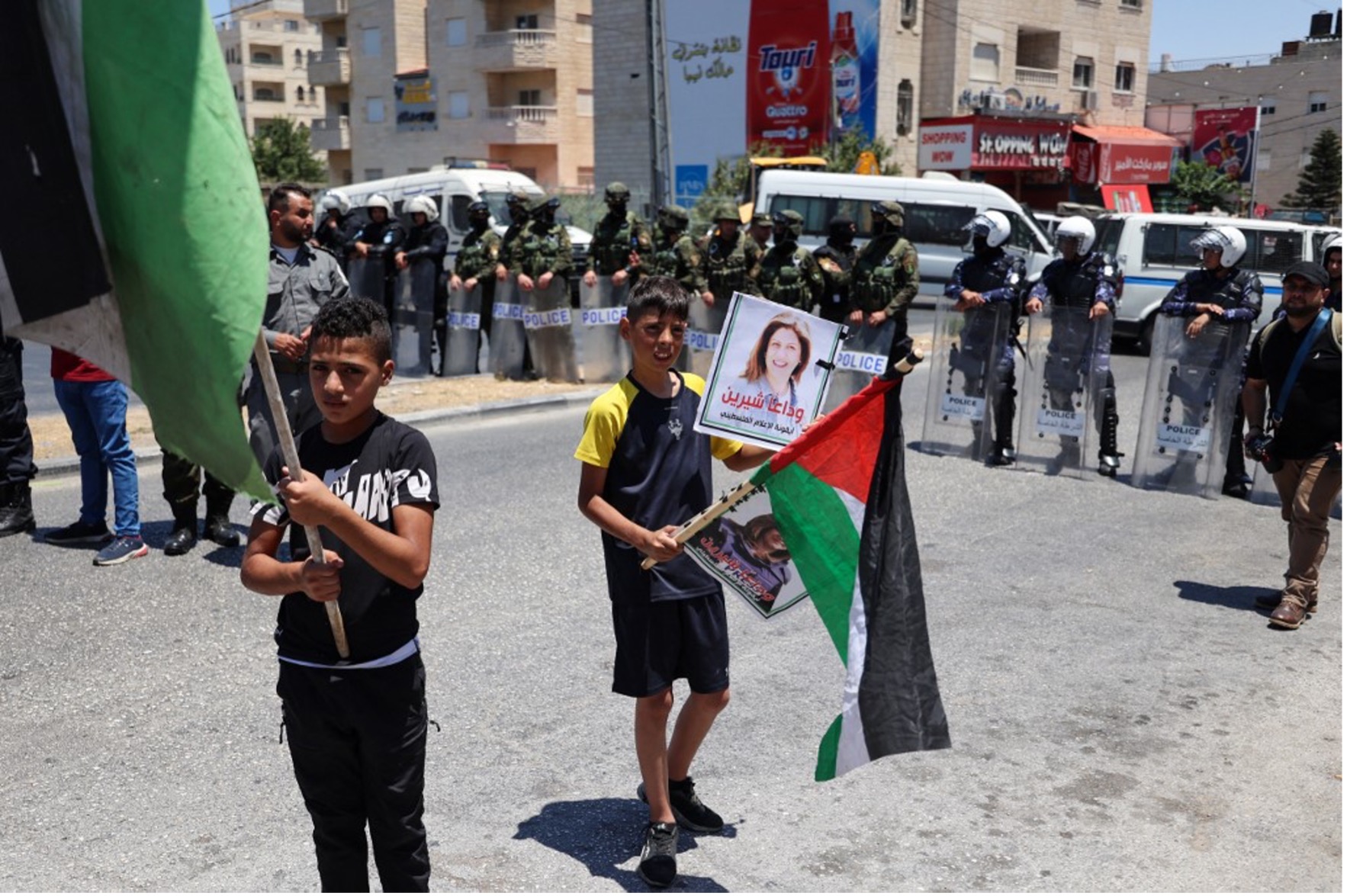 2022年7月15日，美國總統喬．拜登訪問約旦河西岸伯利恆，兩名巴勒斯坦男孩在抗議活動中揮舞國旗，而巴勒斯坦安全部隊站崗。照片來源：ABBAS MOMANI /AFP；耶路撒冷全球華人敬拜中心/提供