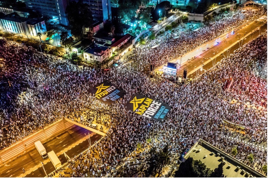 鳥瞰圖顯示，2023年6月24日，以色列特拉維夫，抗議者舉著橫幅示威，反對以色列總理納坦雅胡及其民族主義聯合政府的司法改革。（照片來源：路透社/Oren Alon）