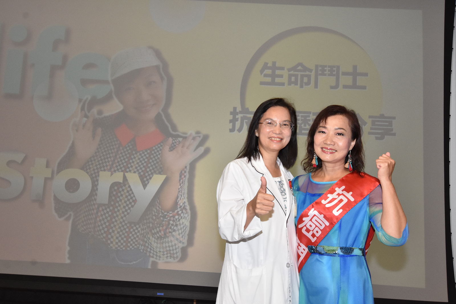 彰基社工部主任（圖左）為陳瓊美女士披掛「抗癌鬥士」榮譽勳帶。