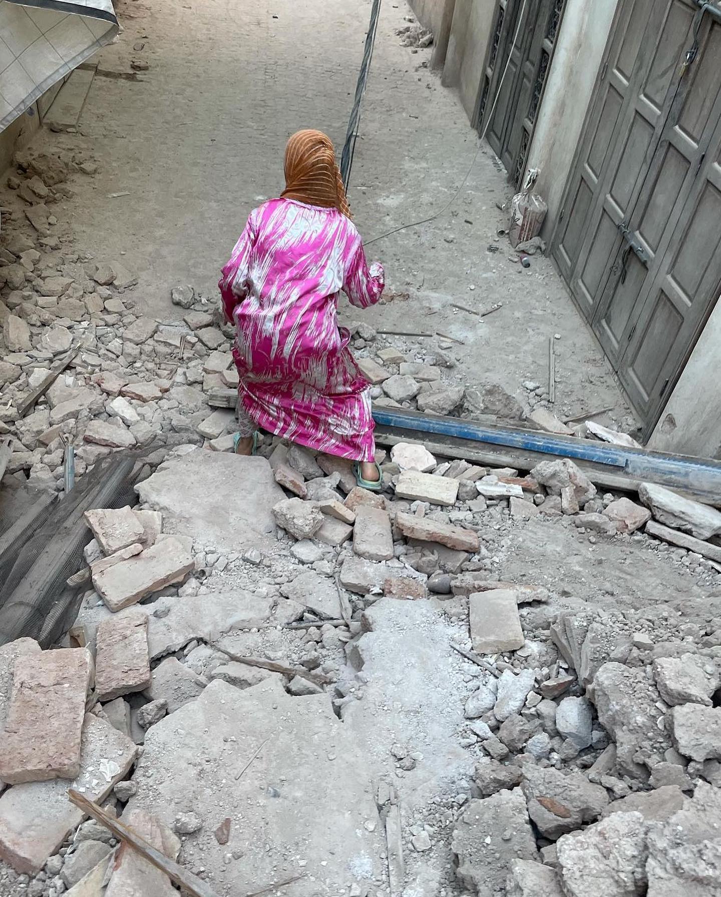 老婦拄著拐杖回到破碎的家園檢視。（翻攝自FB@The Worldwide Tribe）