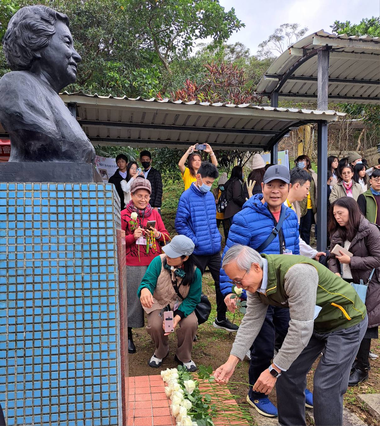 蔡仁松董事長在孫師母銅像前獻上白玫瑰，表達感謝之意。（芥菜種會提供）