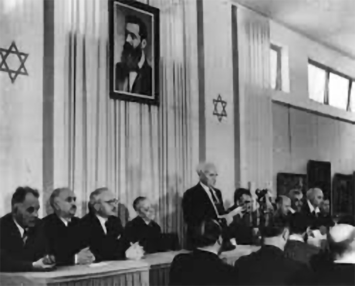 1948年5月14日，特拉維夫，以色列總理大衛．本－古里安在聯合國分治巴勒斯坦後的正式儀式上宣讀以色列國獨立宣言。 （照片來源：Holocaust Encyclopedia）