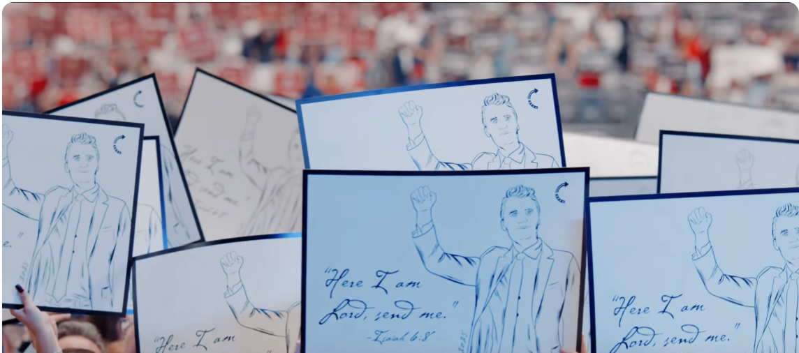 群眾高舉柯克素描標語。（YouTube@Turning Point USA影片截圖）