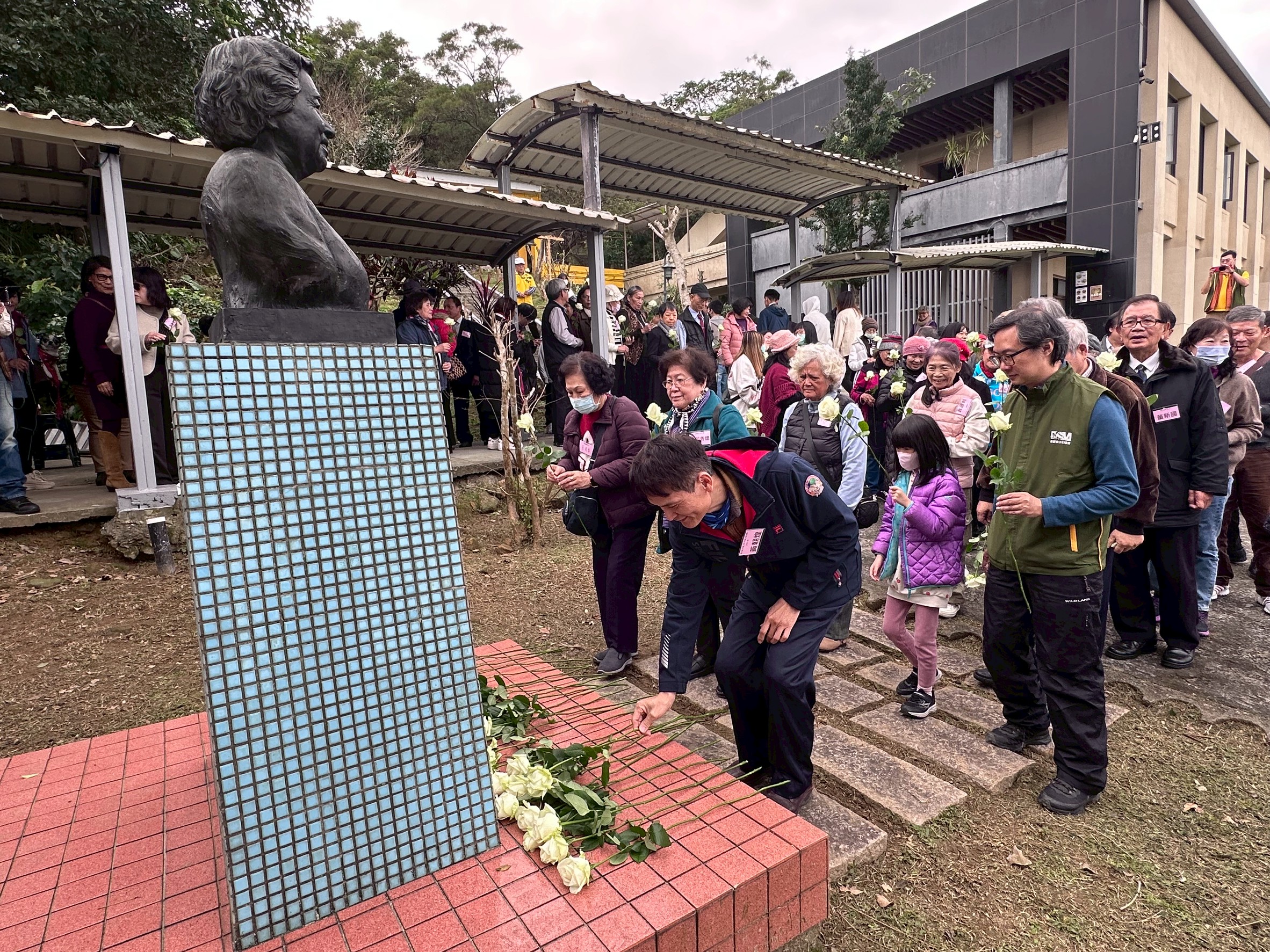 眾人在孫師母銅像前獻上白玫瑰，表達感謝之意。（芥菜種會提供）