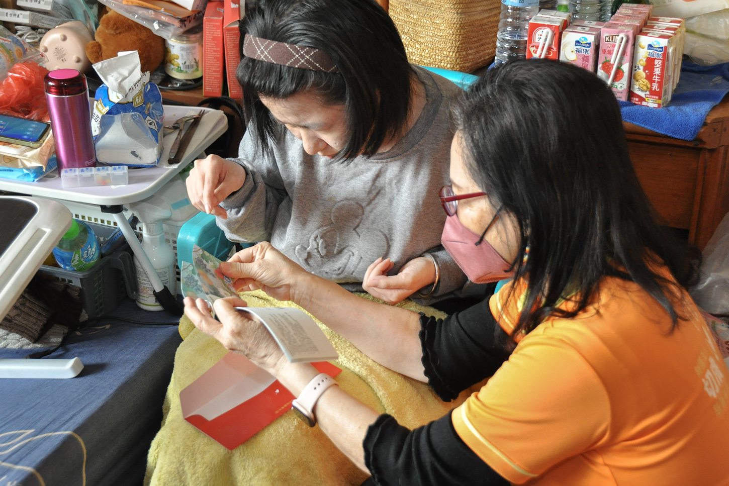 詹執行長（右）陪伴小魚（左）一同細數紅包禮券，神情認真且專注。(彰基提供)