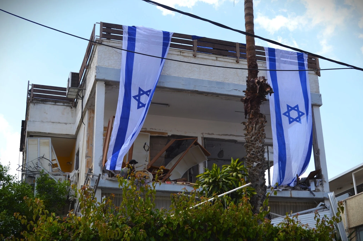 2026年4月5日，以色列國旗覆蓋在一棟被伊朗集束導彈擊中的建築物外牆上。（照片來源：Stav Levaton/Times of Israel）