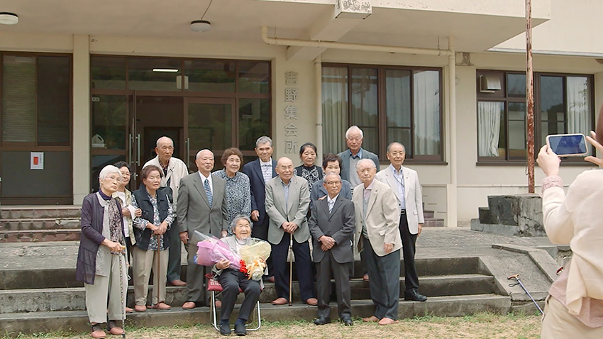 哲代奶奶與小學教過的學生們歡聚合影。（劇照提供：佳映娛樂）